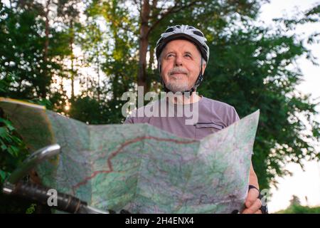 Älterer Mann, der im Sommer beim Radfahren im Wald bei schönem Sonnenuntergang genießt, aktiver Rentner Stockfoto