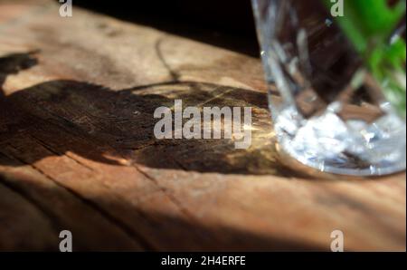 Wasser im Glas mit ätzenden Licht. Streulicht. Kristalllicht und Schatten auf Holzoberfläche. Stockfoto