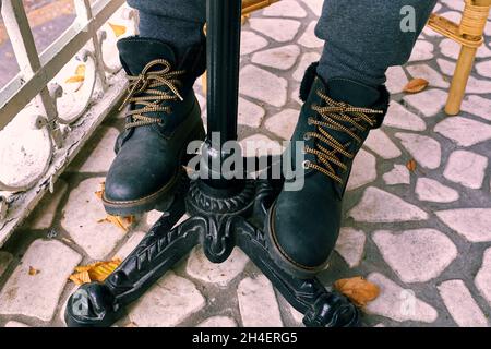 Frauenbeine unter dem Tisch in den modernen schwarzen Winterschuhen. Stockfoto