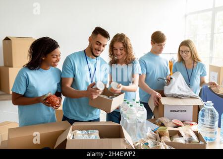 Lebensmittelsortierung. Eine Gruppe junger Freiwilliger verpackt Produkte und Konserven für Spenden in Kartons Stockfoto