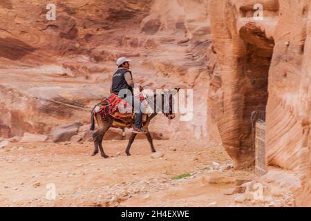 PETRA, JORDANIEN - 23. MÄRZ 2017: Lokaler Junge reitet auf einem Esel in der antiken Stadt Petra, Jordanien Stockfoto