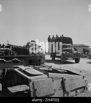 Ein Vintage-Foto um den Mai 1943 ein alliierter Lastwagen voller britischer Soldaten der 8. Armee passiert während des Weltkrieges 2 zerstörte deutsche Panzer in Porto Farina, Tunesien. Aufgenommen am Ende der Schlacht von Tunis, als sich die Afrika Korps schließlich den Alliierten unterwarf. Stockfoto