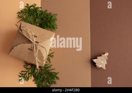 Stilvolle weihnachtskomposition auf braunem und beigen Hintergrund, Geschenke in Bastelpapier, Fichtenzweigen und Holzfigur, Kopierraum. Hochwertige Pho Stockfoto