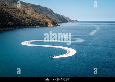 Ein Vergnügungsboot schlängelt sich durch die Bucht von Porto an der Westküste Korsikas Stockfoto
