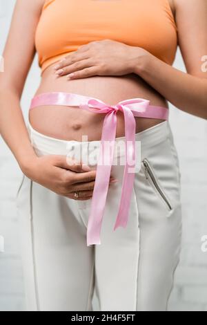 partial view of young pregnant woman with satin ribbon on belly Stockfoto