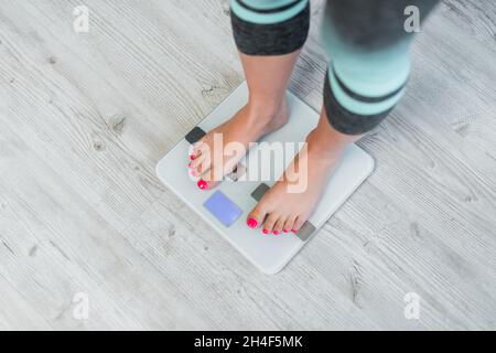 Teilansicht einer barfuß-Frau, die das Körpergewicht auf einer Bodenwaage misst Stockfoto