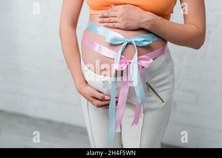 Teilansicht der Schwangeren mit Satinbändern und Schleifen am Bauch Stockfoto