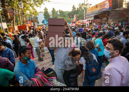 Neu Delhi, Indien-Okt 31 2021: Mann, der während des Diwali-Ansturms vier Koffer auf der Schulter trug. Ein Blick auf den überfüllten Lajpat Nagar Markt, Menschen einkaufen ah Stockfoto
