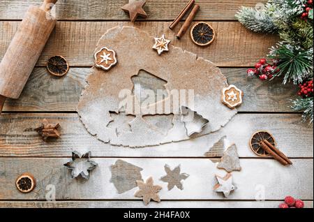 Draufsicht Foto vom Backen von weihnachtsplätzchen. Plätzchenteig und Plätzchenausstecher in Weihnachtsform. Nudelholz und Backartikel auf Rusti Stockfoto