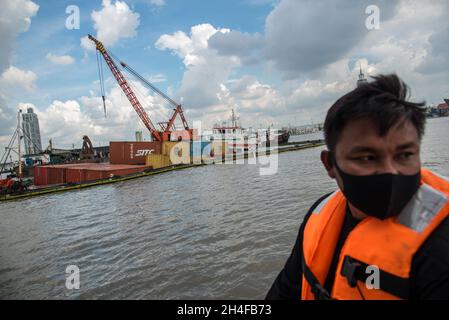 Samut Prakarn, Thailand. November 2021. Ein Zollbeamter beobachtete eine Rettung des angefallenen Frachtschiffes "O.P.K 3", nachdem er vom Frachtschiff "NP Pathum Thani" getroffen wurde.zwei Frachtschiffe mit vollen Containern kollidierten mitten im Fluss vor der Provinzhalle von Samut Prakan. Eines der Frachtschiffe namens „O.P.K 3“ wurde nach dem Zusammenstößen gekentert, aber es wurden keine Besatzungsmitglieder verletzt. Kredit: SOPA Images Limited/Alamy Live Nachrichten Stockfoto