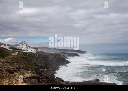 Raue Meere Rollen in die Atlantikküste von Sintra zwischen Praia das Macas und Cabo da Roca unter einem bewölkten Himmel in Portugal Stockfoto