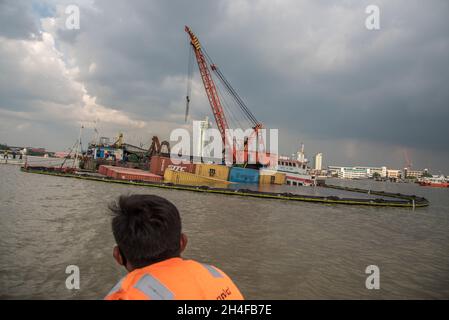 Samut Prakarn, Thailand. November 2021. Ein Zollbeamter beobachtete eine Rettung des angefallenen Frachtschiffes "O.P.K 3", nachdem er vom Frachtschiff "NP Pathum Thani" getroffen wurde.zwei Frachtschiffe mit vollen Containern kollidierten mitten im Fluss vor der Provinzhalle von Samut Prakan. Eines der Frachtschiffe namens „O.P.K 3“ wurde nach dem Zusammenstößen gekentert, aber es wurden keine Besatzungsmitglieder verletzt. Kredit: SOPA Images Limited/Alamy Live Nachrichten Stockfoto