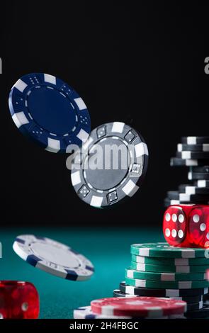 Casino-Chips und -Würfel fliegen über den grünen Tisch des Poker. Stockfoto