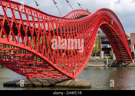 Amsterdam, Niederlande-Mai 2021: Seitenansicht der roten Metallschlange wie Pythonbrug mit hölzernen Stufen, die eine Fußgängerbrücke über den Kanal ist Stockfoto