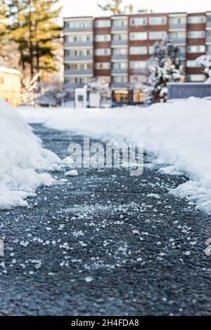 Winterstraße mit Salz zum Schmelzen von Schnee und Haus im Hintergrund Stockfoto