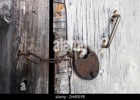 Großes rostiges Schloss an der hölzernen Scheunentür Stockfoto