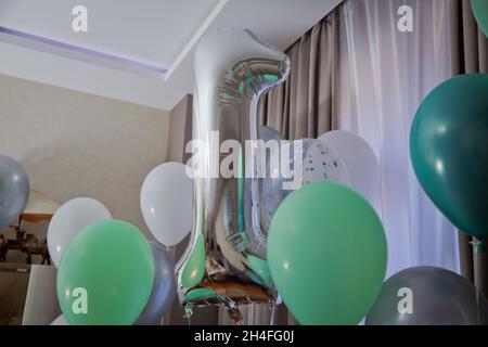 Graue Zahl 1 aus aufblasbarem Ballon isoliert auf weißem Hintergrund. 1 aus Heliumballon. Silber Helium Ballons 1 Zahl . Weiß und grün Stockfoto