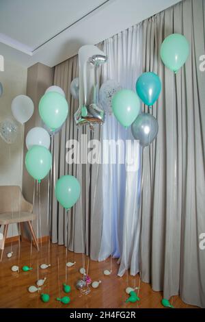 Graue Zahl 1 aus aufblasbarem Ballon isoliert auf weißem Hintergrund. 1 aus Heliumballon. Silber Helium Ballons 1 Zahl . Weiß und grün Stockfoto