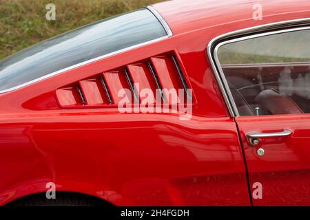 Brummen, Provinz Gelderland, Niederlande, 23.10.2021, Detail von Tür und Seitenfenster des Ford Mustang der ersten Generation in roter Farbe Stockfoto