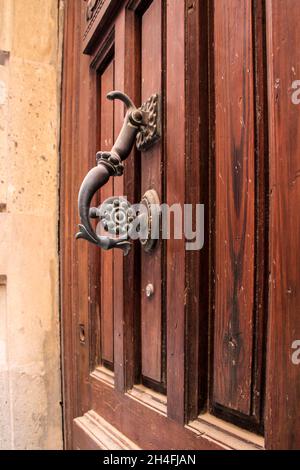 Geschmiedetes Metall Vintage Türklopfer an brauner Holztür in Alicante, Spanien Stockfoto