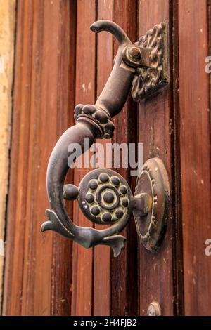 Geschmiedetes Metall Vintage Türklopfer an brauner Holztür in Alicante, Spanien Stockfoto