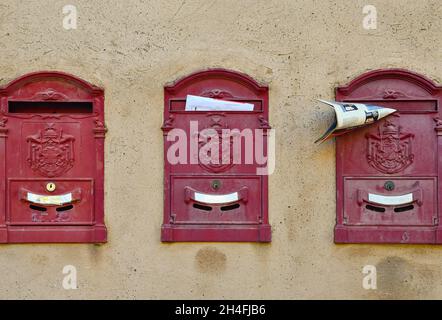 Detail von drei roten Briefkästen, die in einer Reihe an der Wand eines alten Hauses im mittelalterlichen Dorf Castagneto Carducci, Livorno, Toskana, Italien, gehängt wurden Stockfoto