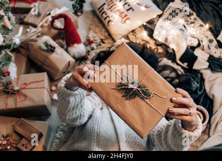 Draufsicht auf die Frau, die am weihnachtsbaum lag und ein eingewickeltes weihnachtsgeschenk hielt. Stockfoto