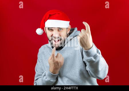 Ein bärtiger Mann in Weihnachtskleidung lächelt launisch und winkt ihm zu Stockfoto