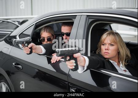 Professionelle bewaffnete Team von weiblichen und männlichen Bodyguards schießen und schützen eine VIP-Prominenten Person in der Auto-Limousine. Bodyguard und VIP Person Security Pro Stockfoto