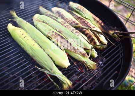 Ein Sommergenuss, frisch geernteter Vollohrsüßer Mais mit Schalen, die draußen gegrillt werden, Kochen in Schalen, um Feuchtigkeit zu bewahren, Hammond, MN, USA Stockfoto