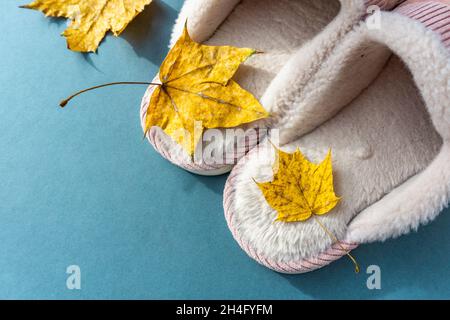 Warme und komfortable Hausschuhe mit gelben Blättern auf grünem Hintergrund. Rosa Farbe. Stockfoto