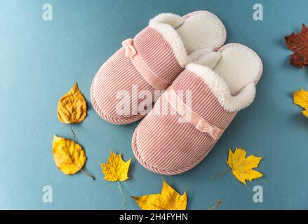 Warme und komfortable Hausschuhe mit gelben Blättern auf grünem Hintergrund. Rosa Farbe. Stockfoto