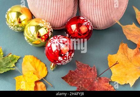Warme und komfortable Hausschuhe mit gelben Blättern und Weihnachtsdekoration auf grünem Hintergrund. Rosa Farbe. Stockfoto