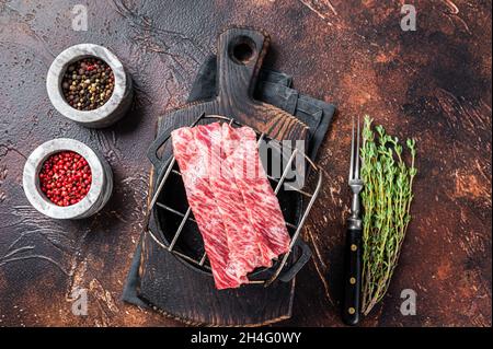 Hochwertige, roh geschnittene Wagyu-Rindfleisch A5-Steaks auf einem Grill für Yakiniku. Japanische Küche. Dunkler Hintergrund. Draufsicht Stockfoto