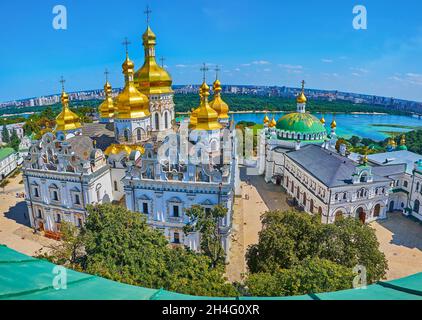 Die goldenen Kuppeln der Geburtskirche der Seligen Jungfrau Maria und das grüne gewölbte Refektorium des Kiewer Klosters Pechersk Lavra mit dem Fluss Dnjepr und Kiew haben Ban hinterlassen Stockfoto