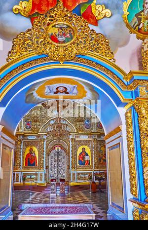 KIEW, UKRAINE - 14. AUGUST 2021: Die goldene Ikonostase der Dormition-Kathedrale ist durch den mit Fresken bedeckten Bogen zu sehen, Kiewer Pechersk Lavra Mo Stockfoto