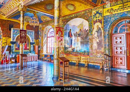 KIEW, UKRAINE - 14. AUGUST 2021: Der reich verzierte Saal der Refektoriumskirche im Kiewer Kloster Pechersk Lavra mit Gemälden und slawischen Inschriften Stockfoto