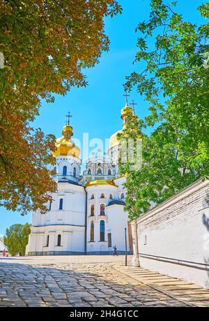 Die schmale Gasse führt zur Dormition-Kathedrale des Kiewer Pechersk-Lavra-Klosters, die durch die üppig grünen Bäume gesehen wird, Kiew, Ukraine Stockfoto