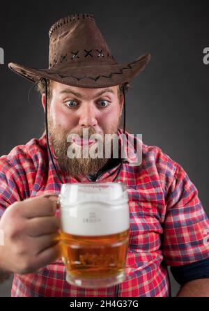 Porträt eines lustigen jungen Mannes, der im Studio Bier aus dem Becher trinkt Stockfoto