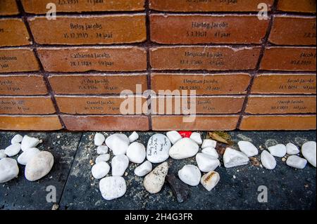 Ein Stein mit dem Namen eines der Opfer, der besagt, dass er vermisst wurde, an der Gedenkstätte.siebzig Jahre nach dem Zweiten Weltkrieg haben mehr als 102,000 Opfer des Holocaust endlich ihr eigenes Denkmal. Dieses nationale Denkmal befindet sich im Herzen des jüdischen Viertels von Amsterdam. Das Denkmal besteht aus einem Labyrinth von Durchgängen, flankiert von zwei Meter hohen Ziegelwänden, die die Botschaft ‘in Erinnerung an' vermitteln. Auf jedem der Ziegel ist der Name jedes Holocaust-Opfers eingeschrieben. Die meisten Menschen, die das Denkmal besuchen, halten Papiere mit den Namen ihrer Angehörigen, die sie Stockfoto