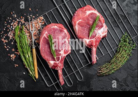 Frische, rohe Tomahawk-Steaks mit Rippenauge auf dem Grill. Schwarzer Hintergrund. Draufsicht Stockfoto
