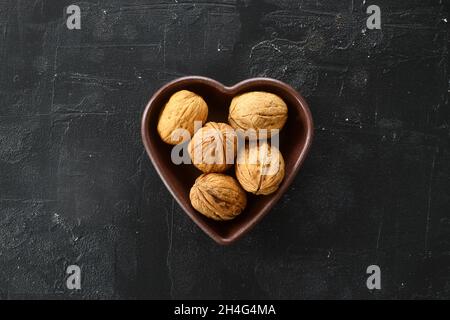 Die Walnüsse in einer herzförmigen Platte. Die Muttern Herz, Herz Gesundheit Produkte, Strukturierte Walnüsse Gesunde Ernährung Protein Stockfoto