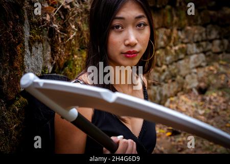 Junge Frau mit einem Cosplay-Outfit für den Sensenmann im Wald Stockfoto