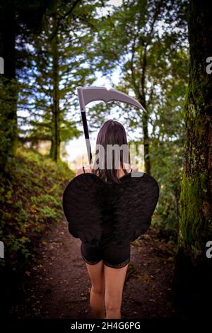 Junge Frau mit einem Cosplay-Outfit für den Sensenmann im Wald Stockfoto