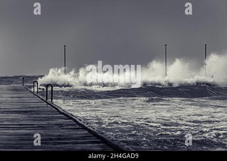 Wellen schluckend Ende des Frankston Pier an einem düsteren stürmischen Tag in schwarz und weiß Stockfoto