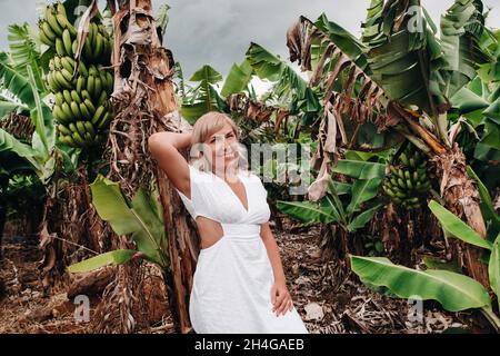 Ein Mädchen auf einer Bananenplantage auf der Insel Mauritius, eine Bananenfarm auf einer tropischen Insel, ein Mädchen in einem weißen Kleid auf einer Plantage in Afrika. Stockfoto