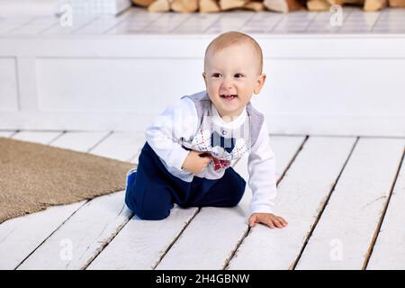 Weiße fröhliche Kleinkind kriecht auf dem Boden im Wohnzimmer. Stockfoto