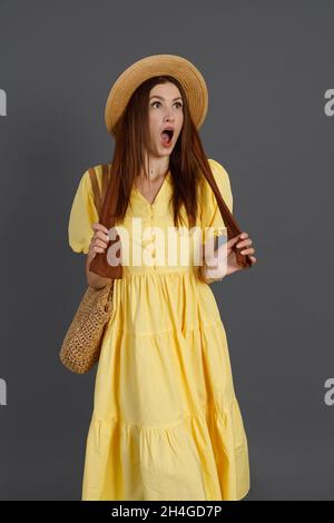 Schockierte Frau in gelbem Kleid, die im Studio steht Stockfoto