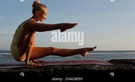 Schöne Frau, die Yoga am Strand macht. bali Stockfoto