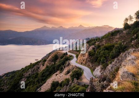 Die Straße D824 schlängelt sich entlang der Küste von Capu Rossu in Richtung Piana an der Westküste Korsikas, während die Morgensonne die Dista erleuchtet Stockfoto